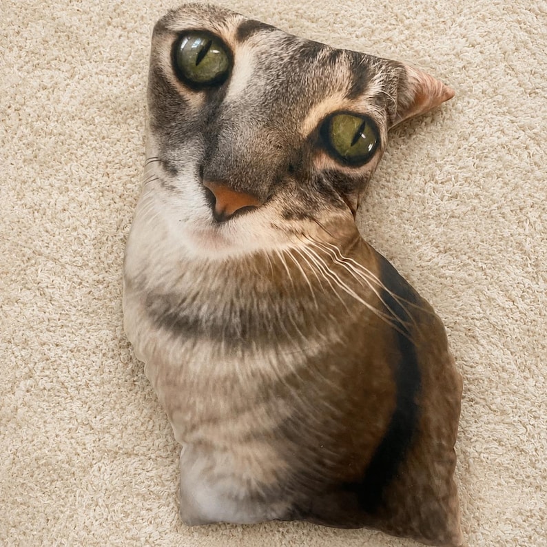 Die-cut pillow shaped like a green-eyed tabby cat's head